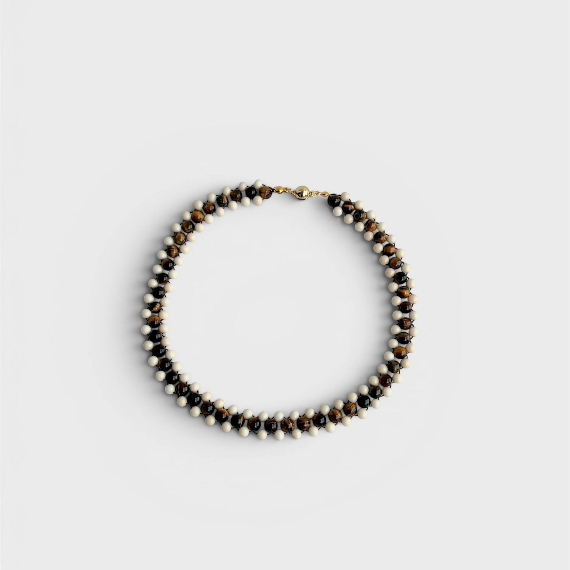 Hollywood Road Stories handcrafted statement necklace featuring alternating tiger's eye and white beads with gold clasp.