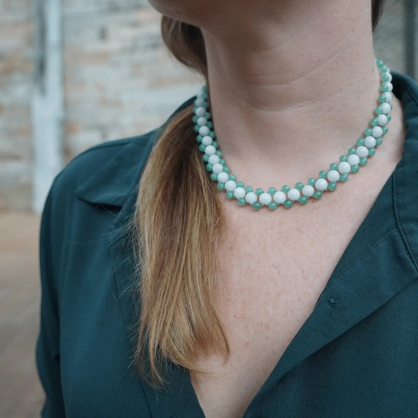 Hollywood Road Stories beaded choker with alternating white and sage green beads worn on a model in a dark shirt