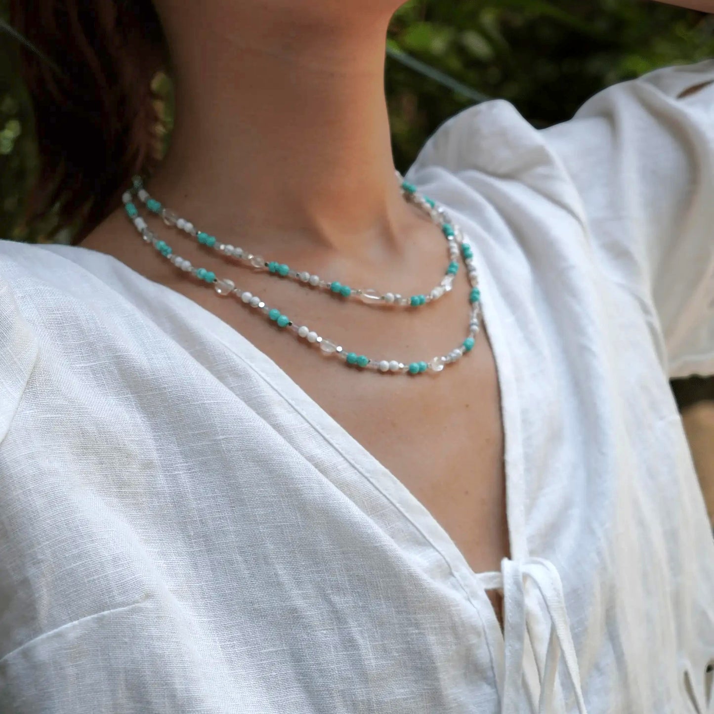 Hollywood Road Stories multi-strand beaded necklace with turquoise, white, and crystal beads worn with a white linen top.