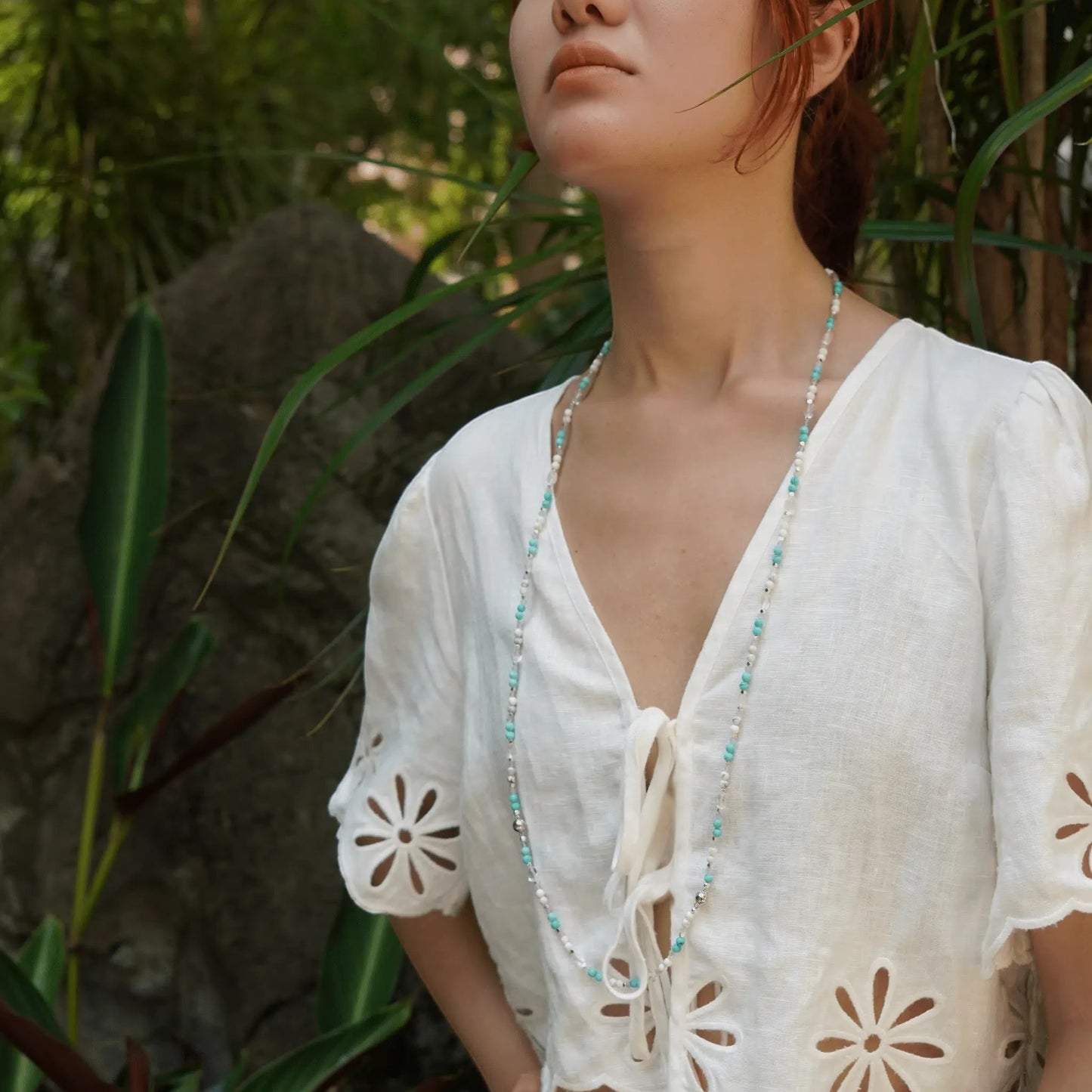 Hollywood Road Stories multi-strand beaded necklace with turquoise, white, and crystal beads on a model outdoors.
