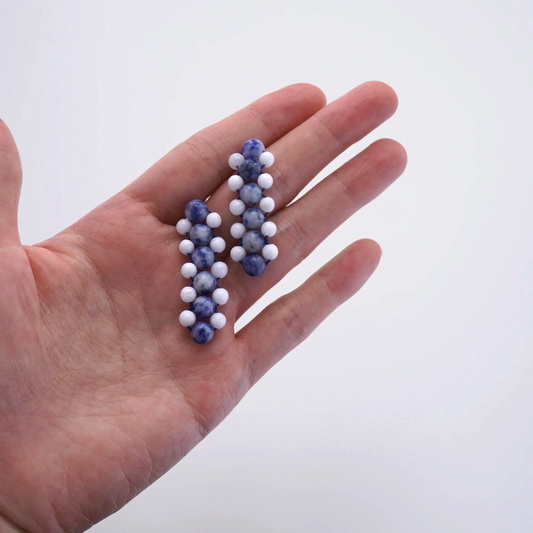 Hollywood Road Stories handcrafted statement earrings with blue marbled and matte white beads held in a palm.