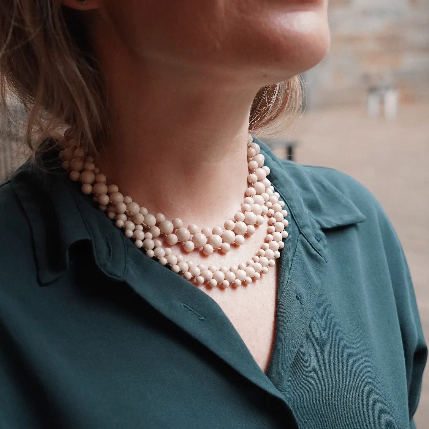 Hollywood Road Stories double strand cream beaded necklace worn by a woman in a dark green blouse