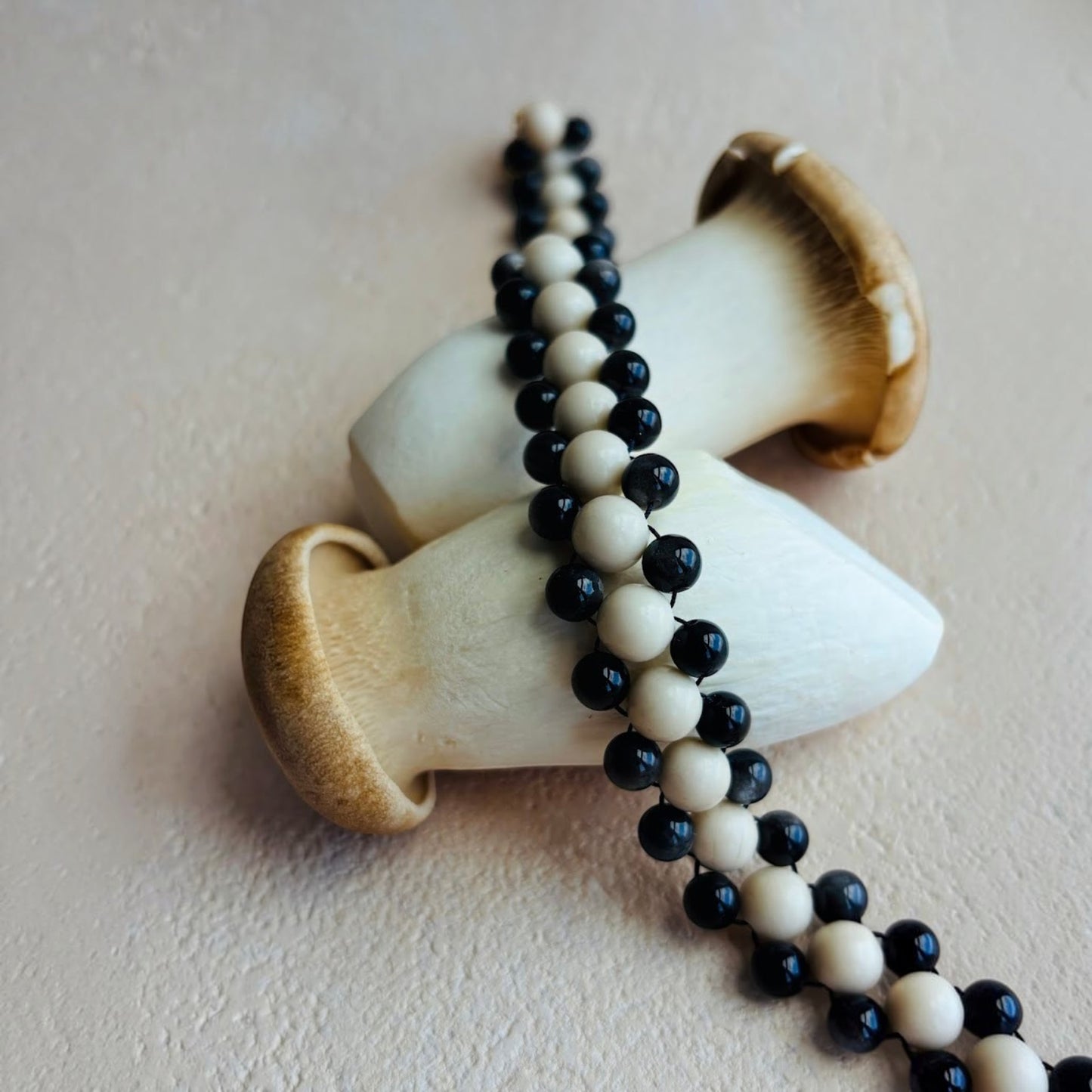 Hollywood Road Stories double strand necklace with alternating cream and charcoal black beads on a neutral background