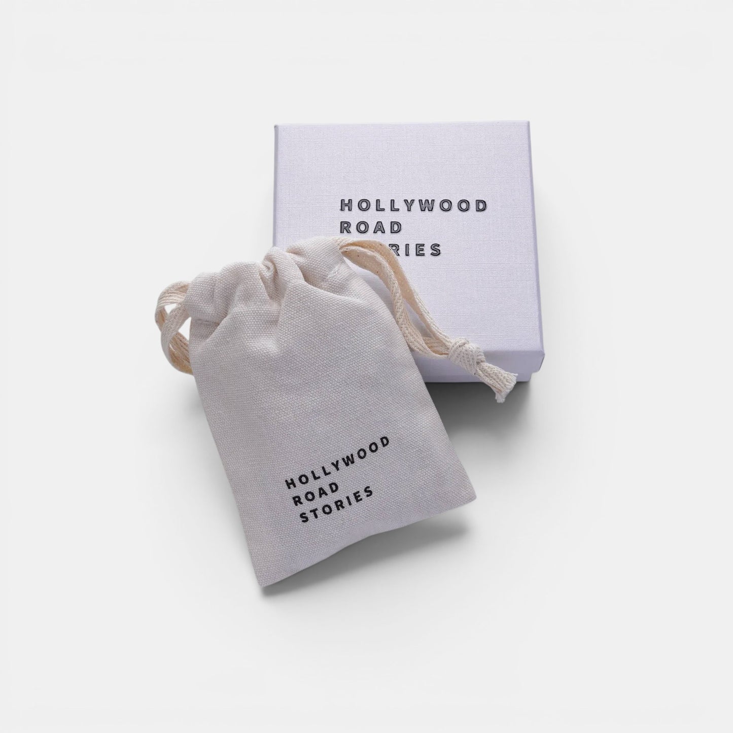 Hollywood Road Stories branded white cotton drawstring jewelry pouch and matching gift box on a neutral background.