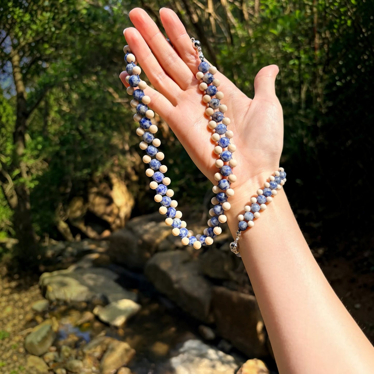 Hollywood Road Stories Aberdeen blue sodalite and cream jasper beaded choker necklace held in a hand outdoors.